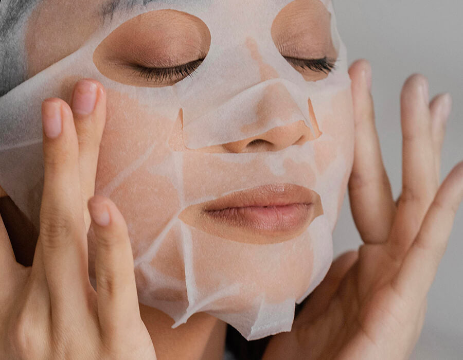 A woman smoothing a sheet mask onto her face