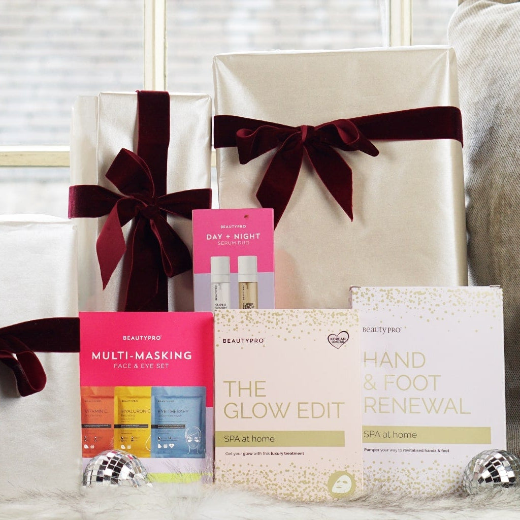 Gifts wrapped in white paper with red ribbons on a couch.