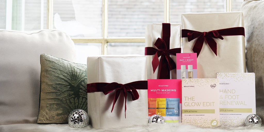 Gifts wrapped in white paper with red ribbons on a couch.