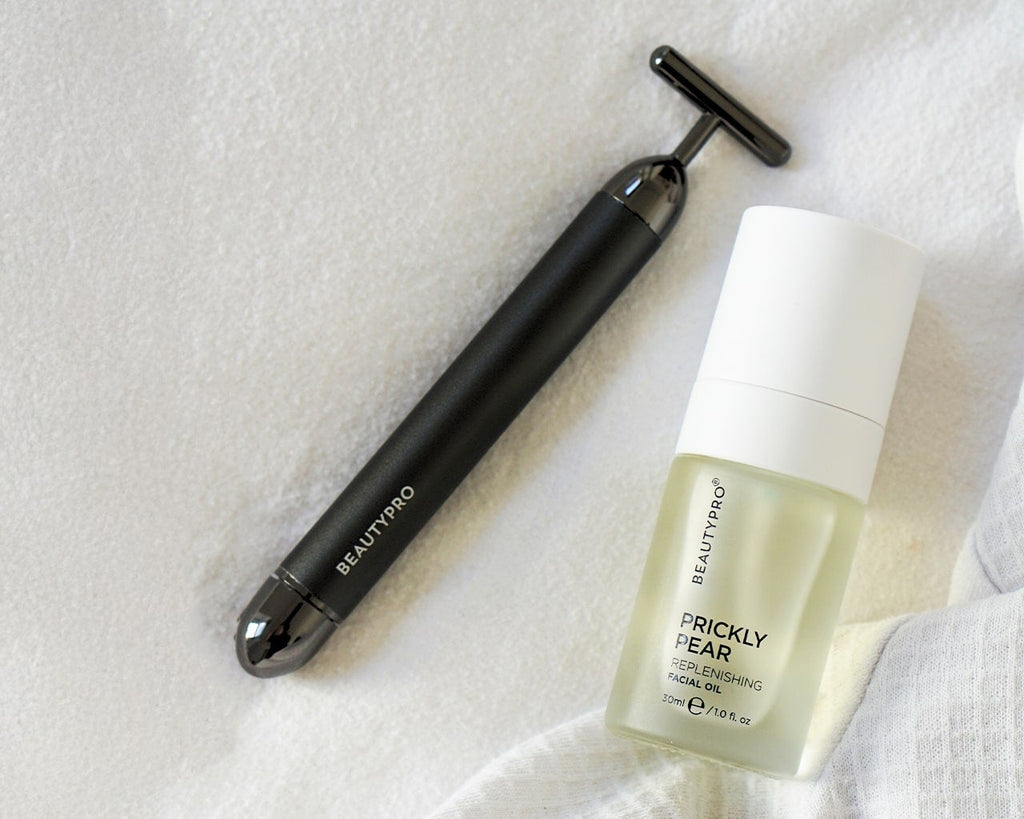 Beauty tool and skincare product on a textured white surface
