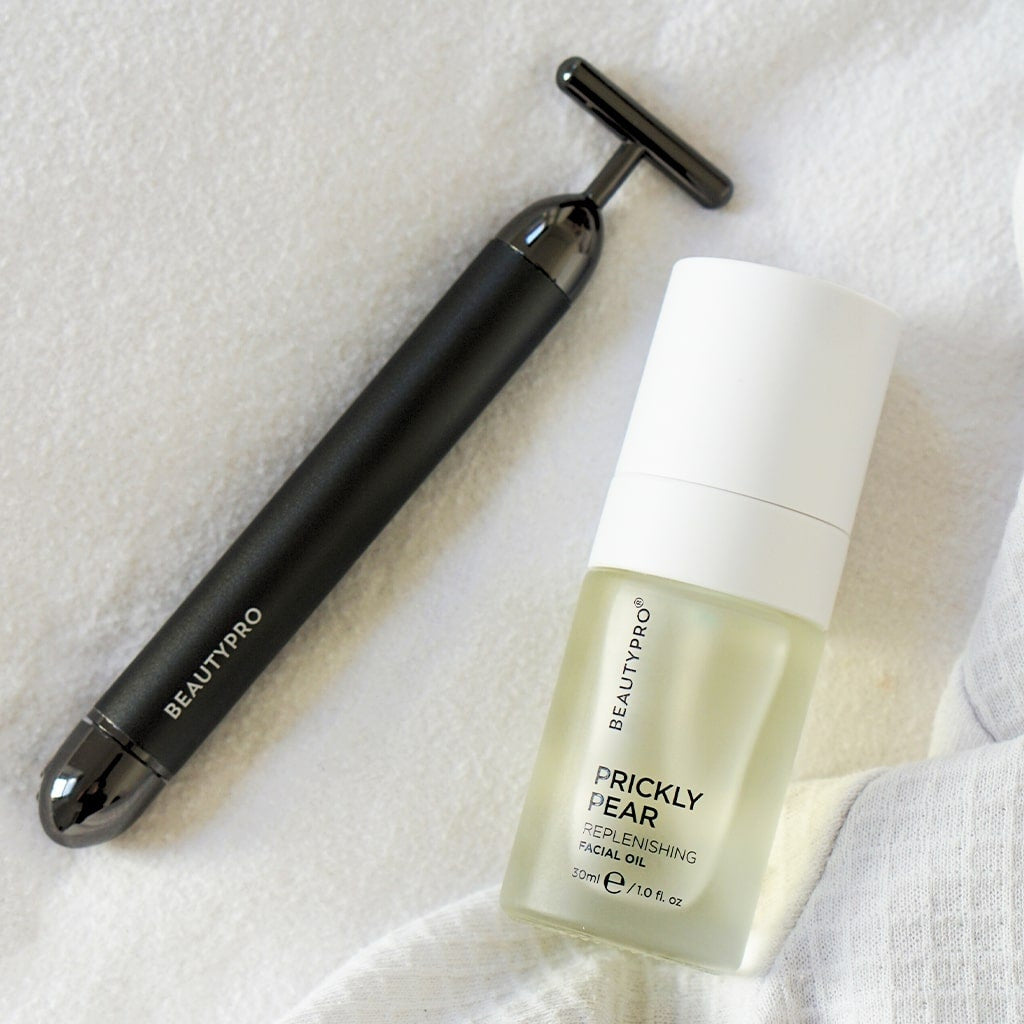 Beauty tool and skincare product on a textured white surface