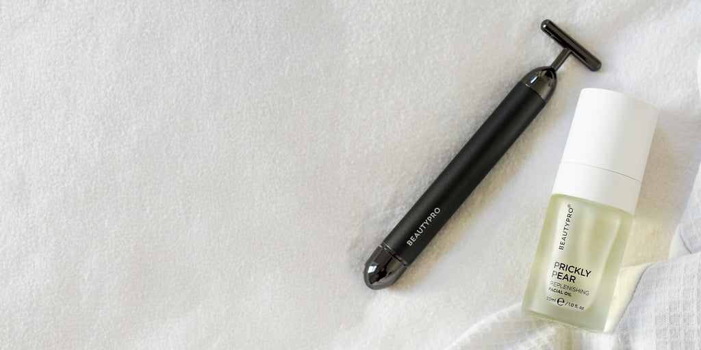 Beauty tool and skincare product on a textured white surface