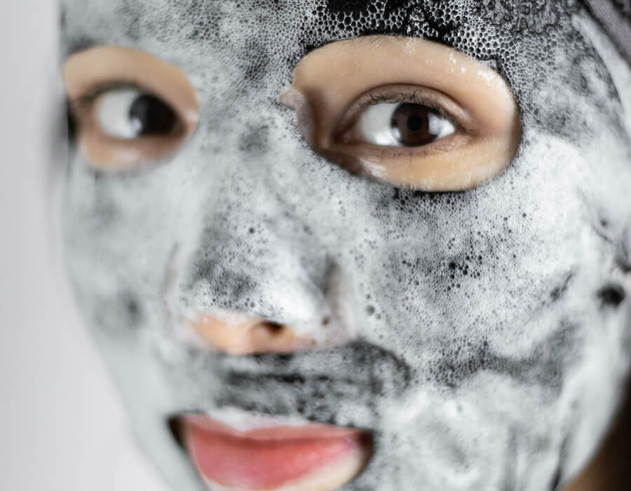 The detoxifying mask in use - a black mask with foam bubbling on top of it.