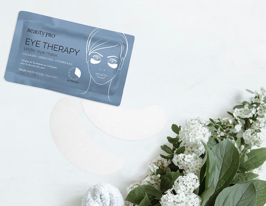 A single eye therapy sachet on a white background with green foliage and white flowers.