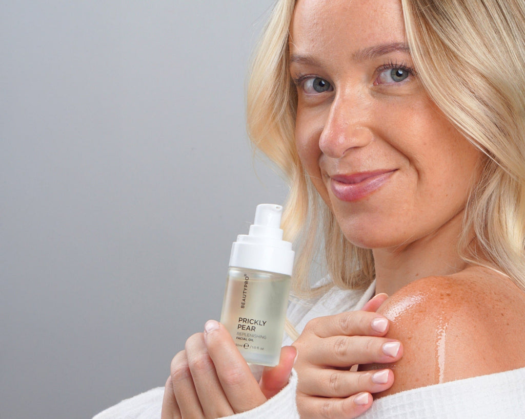 Woman holding a skincare product with a gray background