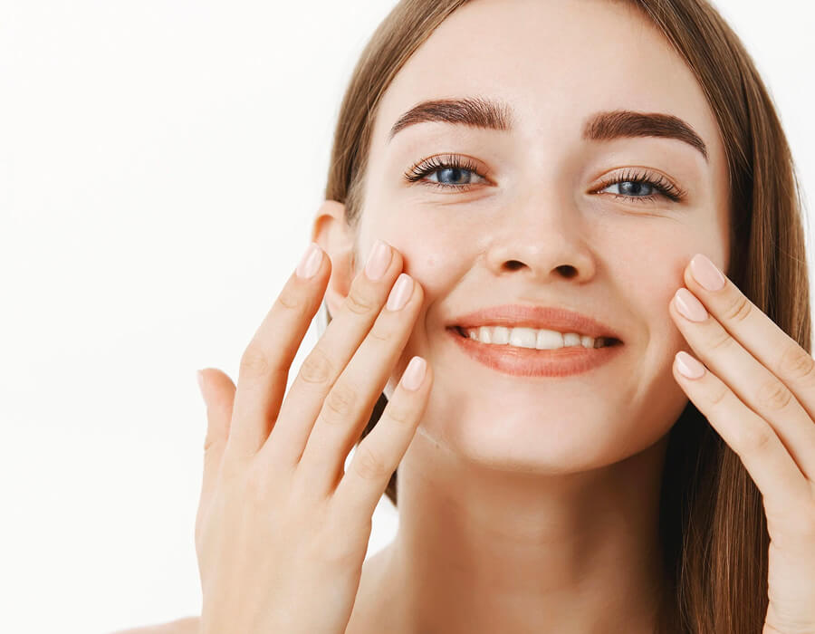 A woman rubbing serum into her face
