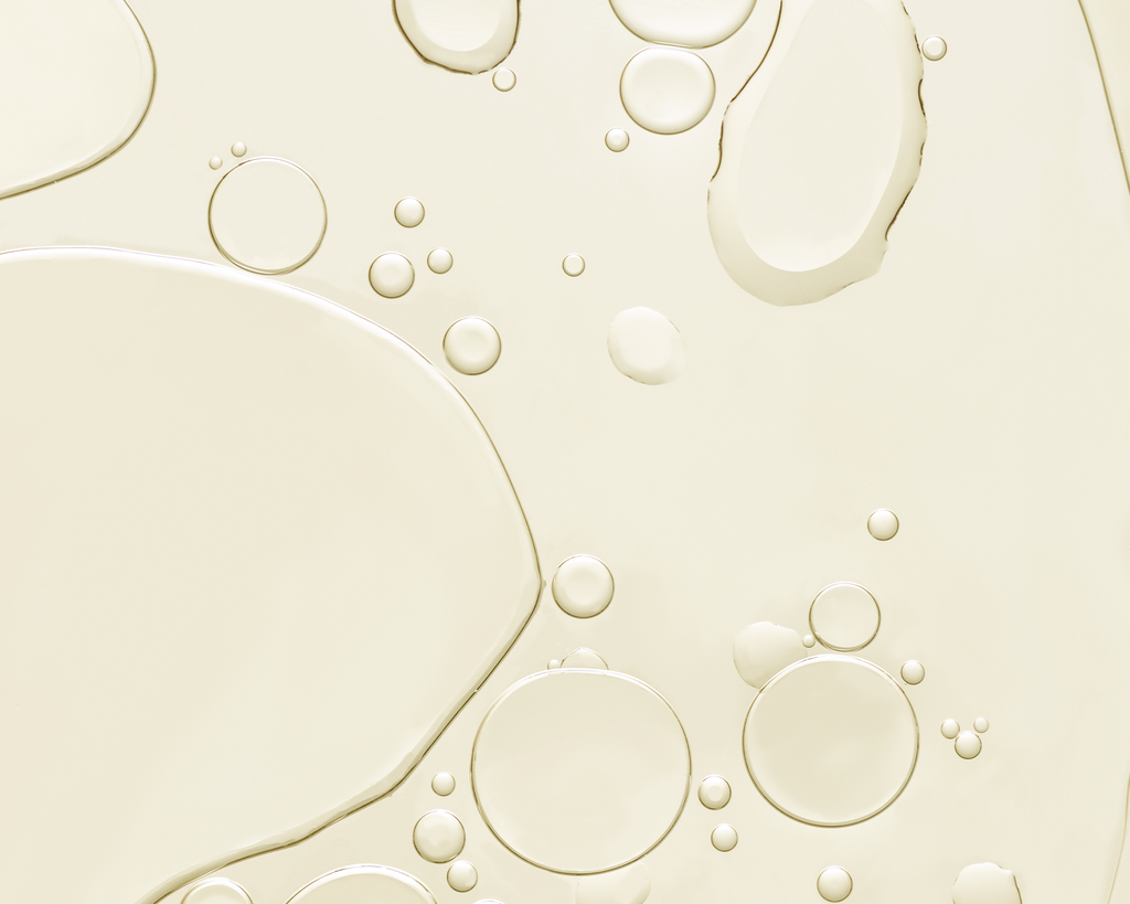 Close-up of oil bubbles on a beige liquid surface
